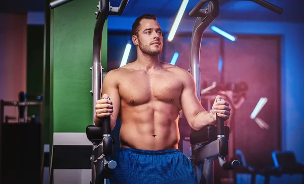 Bodybuilder fort faisant l'excersise sur des barres parallèles dans un centre de fitness moderne — Photo