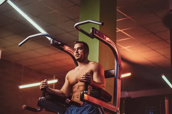 Strong bodybuilder doing excersise on a parallel bars in a modern fitness center — Zdjęcie stockowe