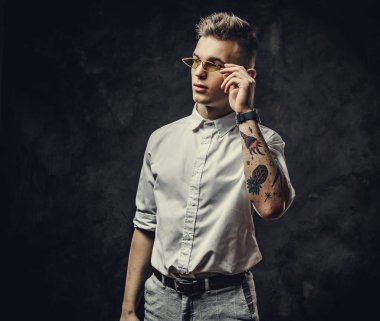 Yakışıklı, kendine güvenen ve karanlık bir stüdyoda yalnız poz veren genç bir erkek.