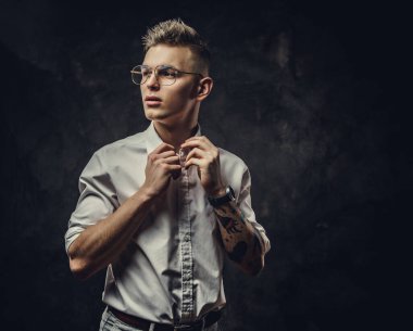 Stüdyoda poz veren şık görünümlü genç bir adam, ilgili görünüyor. Gri bir arkaplanda izole edilmiş