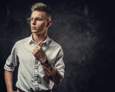 Patronluk taslayan genç bir erkek stüdyoda poz veriyor. Gri bir arka planda izole edilmiş.