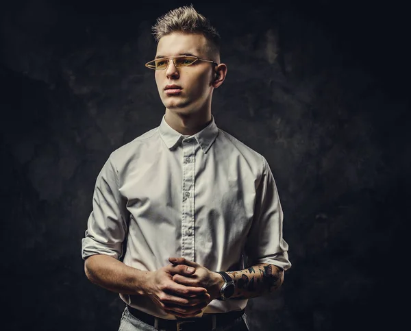 Denken tattoed jonge man kijken zelfverzekerd en poseren geïsoleerd in een donkere studio — Stockfoto