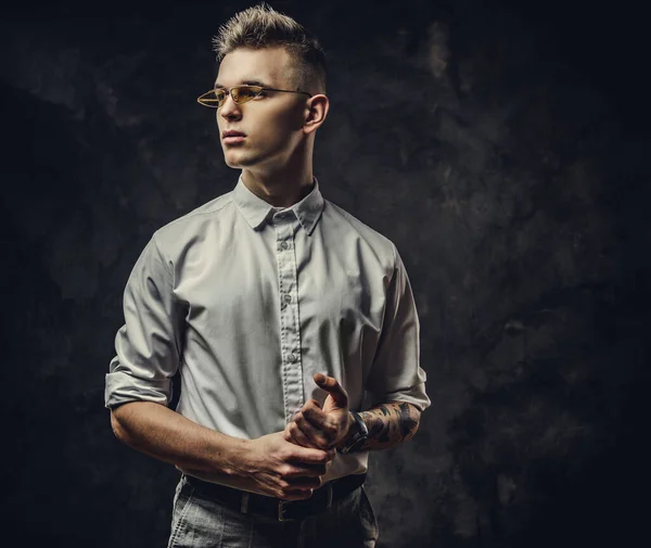 Handsome tattoed young male looking confident and posing isolated in a dark studio