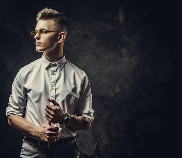 Hombre joven tatuado confiado que se ve confiado y posando aislado en un estudio oscuro frente al fondo gris — Foto de Stock