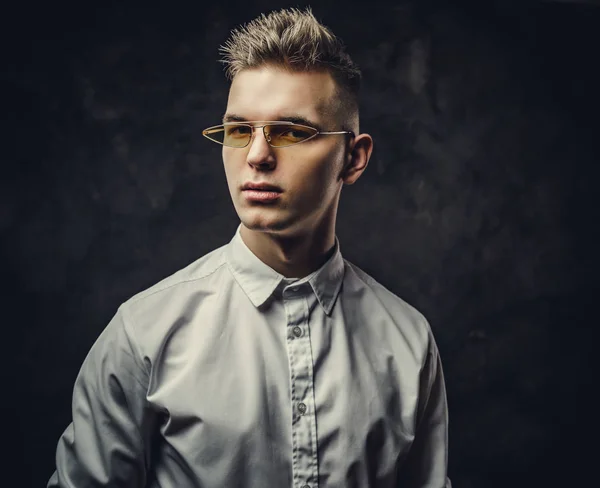 Confident and interested young male looking on the camera isolated in a dark studio in front of the grey background — Stock Photo, Image