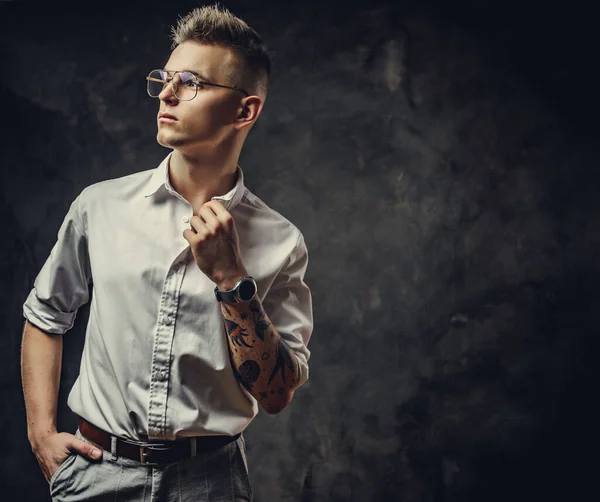 Bossy looking young adult male posing in a studio, isolated on a grey background