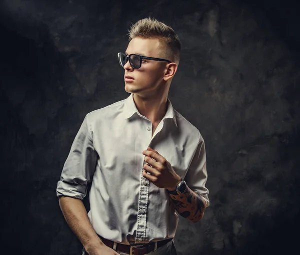 Cool tattoed young male looking confident and posing isolated in a dark studio in front of the grey background — Stockfoto