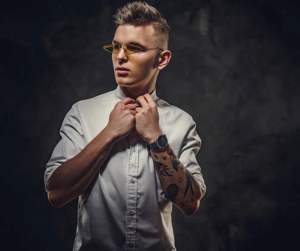 Hombre adulto joven bien parecido posando en un estudio, sosteniendo su cuello, aislado sobre un fondo gris — Foto de Stock