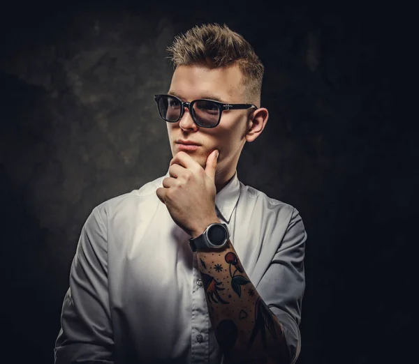 Bossy looking young adult male posing in a studio while holding his chin, isolated on a grey background — Stock Photo, Image