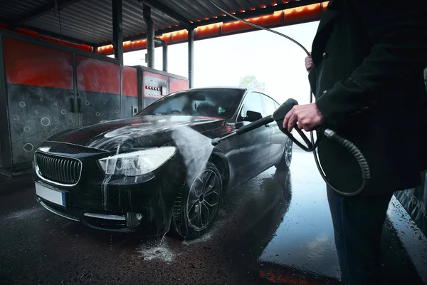 Ręce żołnierza myjącego samochód na zewnątrz w myjni samochodowej pod wysokim ciśnieniem wody — Zdjęcie stockowe