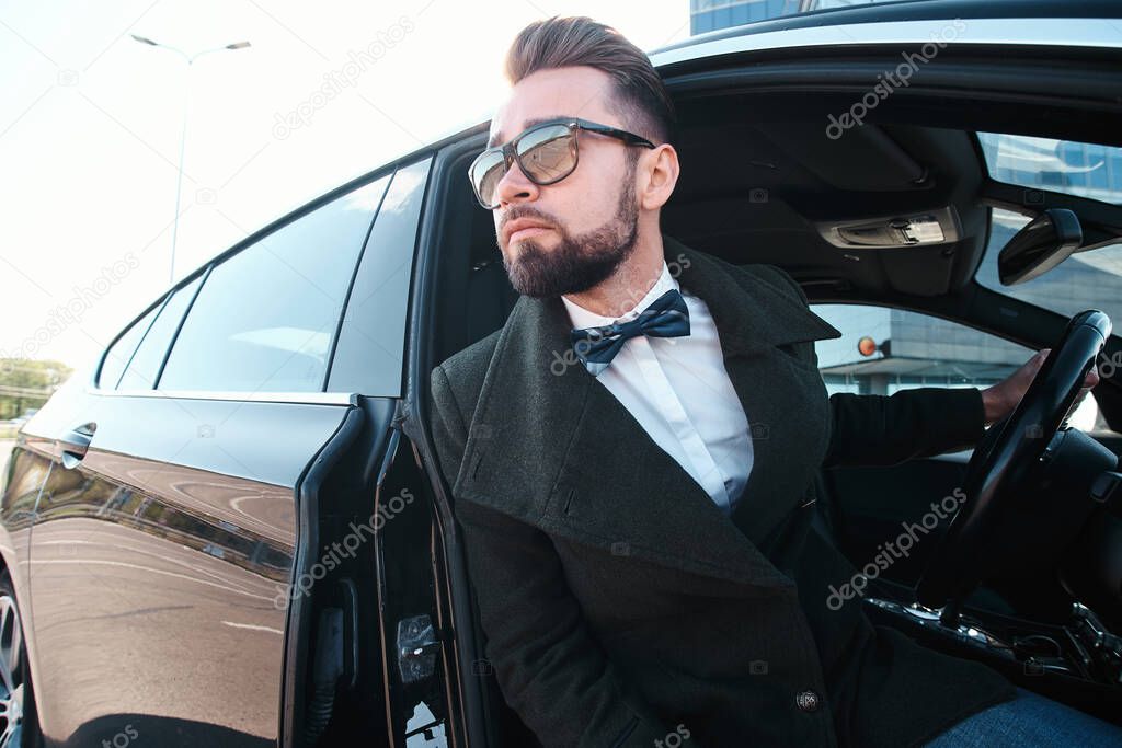 Young handsome adult businessman getting out of his car, close up portrait