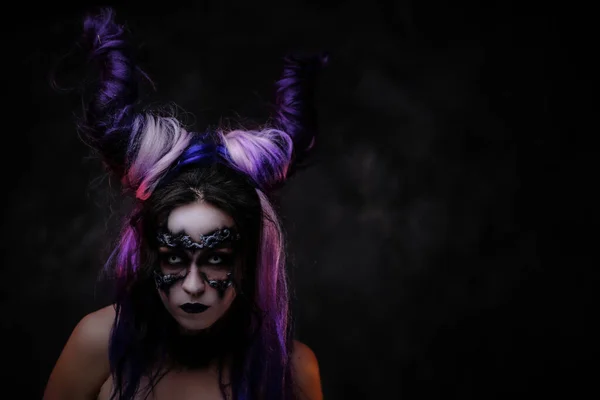 Mujer joven con maquillaje místico oscuro y cuernos violetas posando en un estudio —  Fotos de Stock