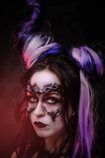 Молодая женщина с таинственным темным макияжем и фиолетовыми рогами позирует в студии. Вертикальное фото — стоковое фото