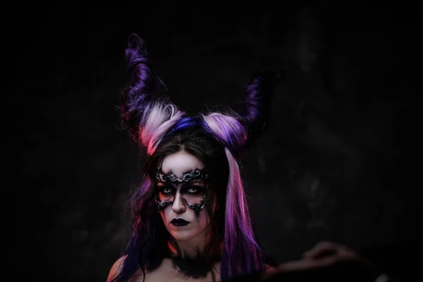 Cosplayer ragazza indossa scuro demoniaco make up e corna in posa in uno studio su uno sfondo scuro — Foto Stock