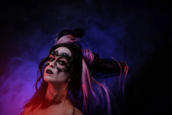 어둠의 악마 옷을 입고 어두운 배경에 스튜디오에 있는 뿔을 가진 코스프레 여자 — 스톡 사진