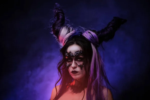 Siyah şeytani makyajlı Cosplayer kızı ve karanlık bir arka planda stüdyoda poz veren boynuzları. — Stok fotoğraf