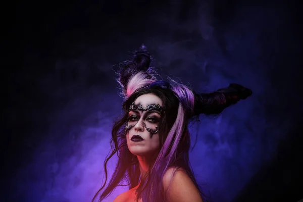 Młoda kobieta ubrana w ciemny makijaż i fioletowe rogi, pozująca w studio ze smke — Zdjęcie stockowe