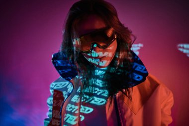Metin projeksiyonu üzerinden canlı bir neon stüdyoda poz veren dövmeli genç bir yarışçının portresi.