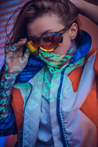 Vacker kaukasisk kvinna i cyber stil poserar över neon projektion i en levande studio, närbild skott — Stockfoto