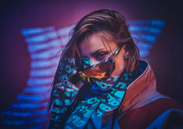 Encre attrayant femelle posant dans un néon vives lumières d'un studio avec du texte, l'air confiant — Photo