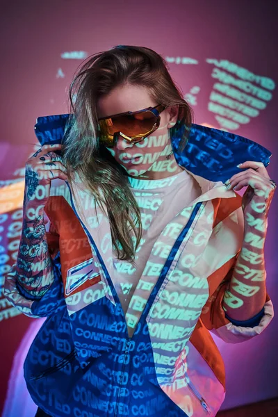 Tinta fêmea atraente posando em um néon luzes vívidas de um estúdio com texto, olhando confiante — Fotografia de Stock
