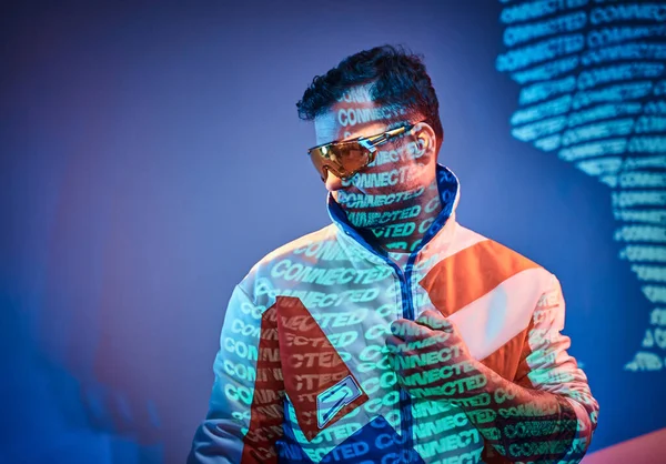 Tinta atraente masculino posando em um néon luzes vívidas de um estúdio com texto, olhando confiante — Fotografia de Stock