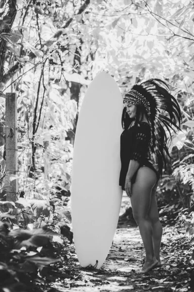 サーフィンボードで森の中にポーズを取る半ヌード女性の黒と白の写真、 aztecの概念的な外観 — ストック写真