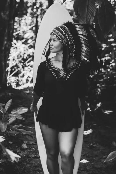 マヤのインドのヘッドウェアを着てサーフィンボードで森の中にポーズを魅力的な女性。白黒写真. — ストック写真