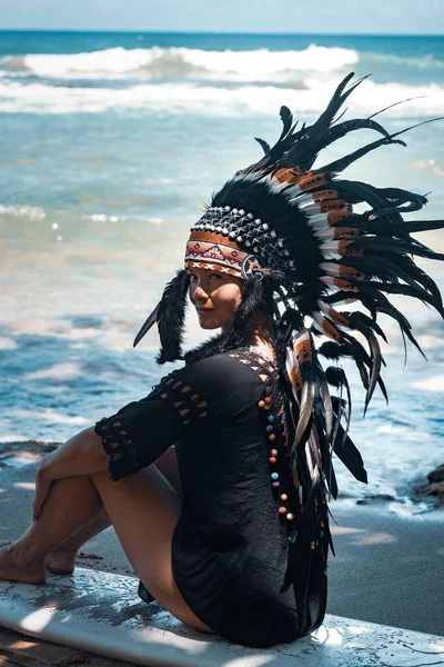 Nahaufnahme Porträt einer halbnackten Frau, die auf einem Surfbrett an einem sonnigen Strand in der Nähe des Meeres sitzt, konzeptioneller Aztec-Look — Stockfoto