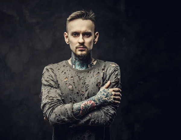 Tattooed male model posing in a dark grey background wearing ripped long-sleeved jumper — Stock Photo, Image