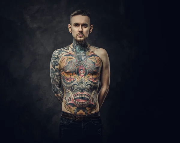 Чортова чоловіча модель позує в темній студії з сірим тлом з напівголим татуюванням тіла . — стокове фото
