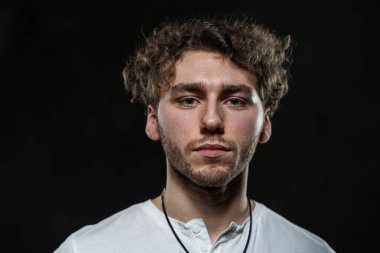 Yakışıklı ve sıradan görünümlü bir adam karanlık arka planda fotoşop için poz veriyor.