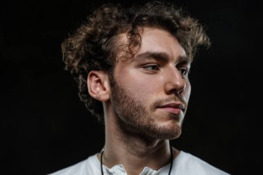 Yakışıklı ve sıradan görünümlü bir adam karanlık arka planda fotoşop için poz veriyor.