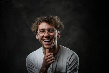 Stüdyoda fotoğraf çekimi için poz veren sıradan kıyafetler ve tılsım giyen gülümseyen bir öğrenci.