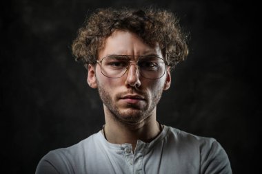 Ciddi ve düşünceli bir öğrenci stüdyoda karanlık bir arkaplanda poz veriyor.