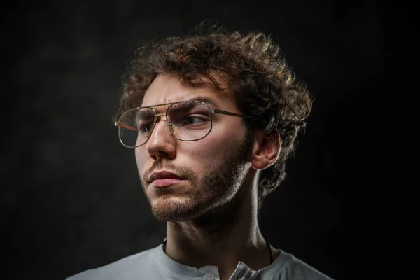 Estudiante serio y considerado posando sobre un fondo oscuro en el estudio — Foto de Stock