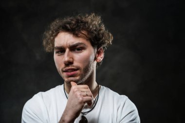 Yakışıklı ve sıradan görünümlü bir adam karanlık arka planda fotoşop için poz veriyor.