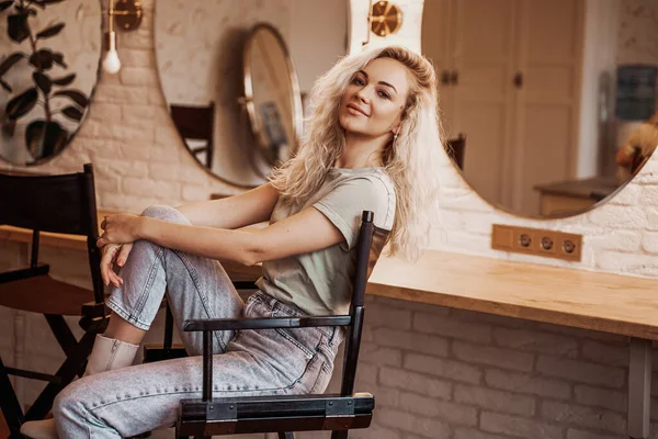Avslappnad och moderiktig kvinna med blont hår poserar i en make up studio — Stockfoto