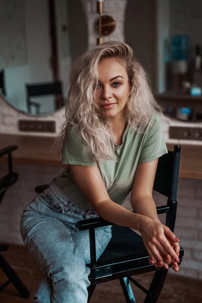 Avslappnad och moderiktig kvinna med blont hår poserar i en make up studio — Stockfoto