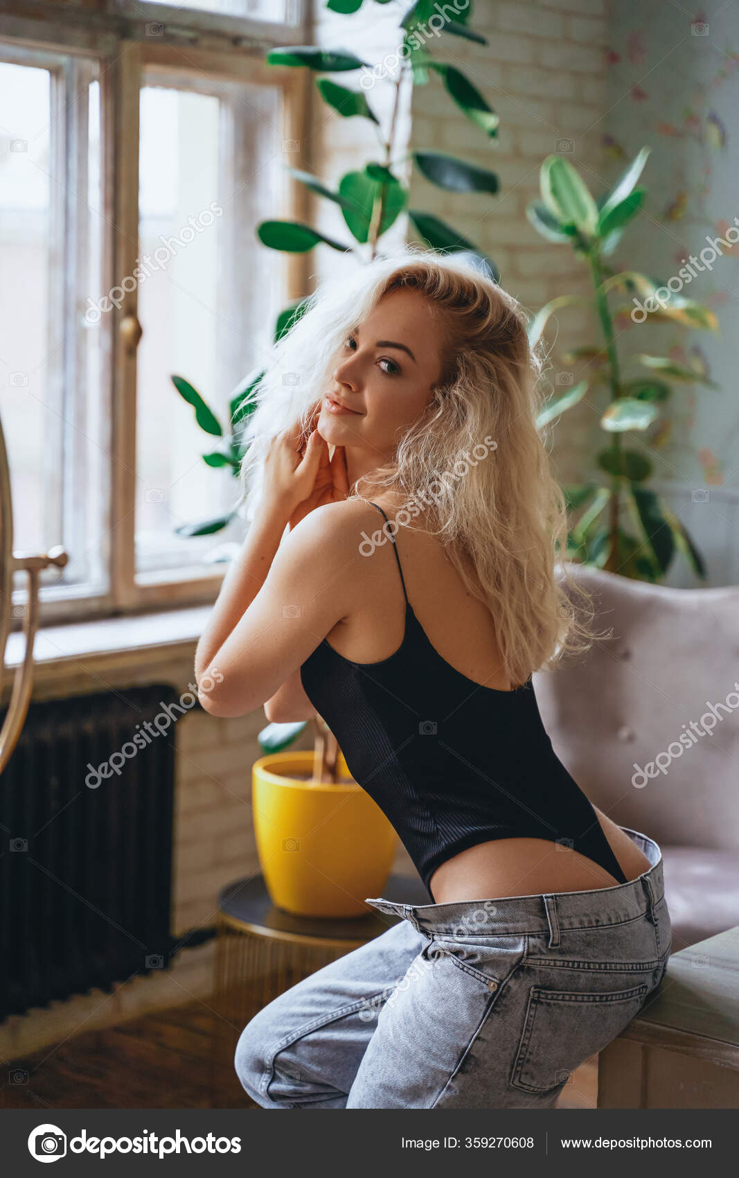 Portrait of a sensual young woman with curly hair sitting in a bright room  on a table Stock Photo by ©fxquadro 359270608