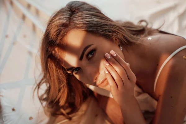 Närbild skott av sexig och passform kvinna som ligger på en säng i en spets underkläder ser förförisk bland stjärnan konfetti — Stockfoto