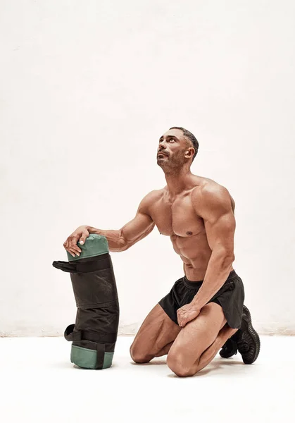 强壮的成年男子 赤身裸体地站在地上 身穿黑色短裤 仰视身体 头戴重物袋 — 图库照片