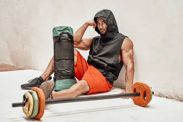 Athletic Man Sitting Floor Wearing Cape Holding Sport Gear Isolated — Stock Photo, Image