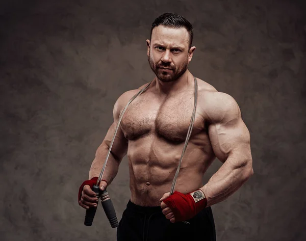 Seriöser Bodybuilder Sportbekleidung Posiert Mit Springseil Und Blickt Einem Dunklen — Stockfoto