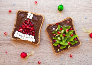 Çocuklar parti - çikolatalı krema, nar Santa şapka ve kivi Noel ağacı ahşap masa ile tost için Noel sağlıklı kahvaltı veya tatlı fikir