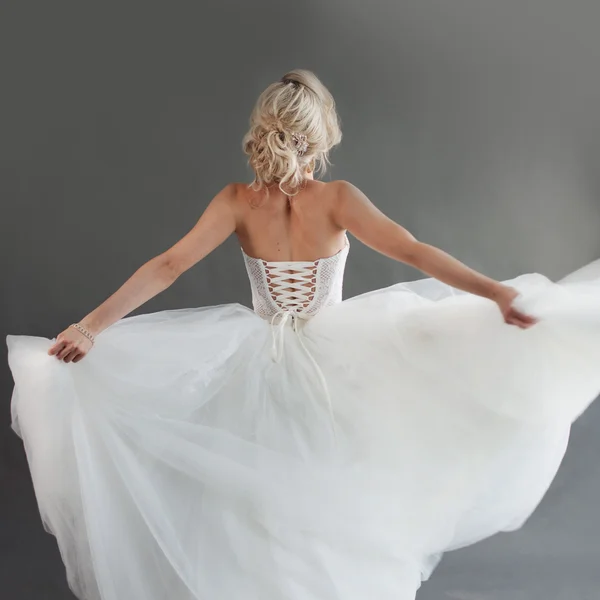 Dançando noiva jovem em vestido de noiva de luxo. Menina bonita de branco. Voltar, fundo cinza — Fotografia de Stock