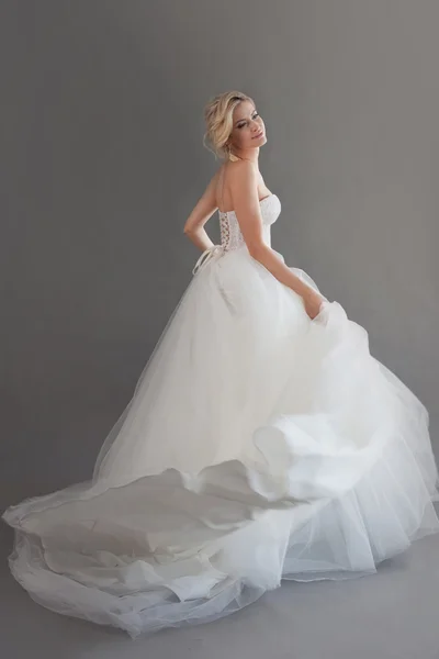 Jovem noiva encantadora em vestido de casamento luxuoso. Menina bonita de branco. Emoções de felicidade, fundo cinza — Fotografia de Stock
