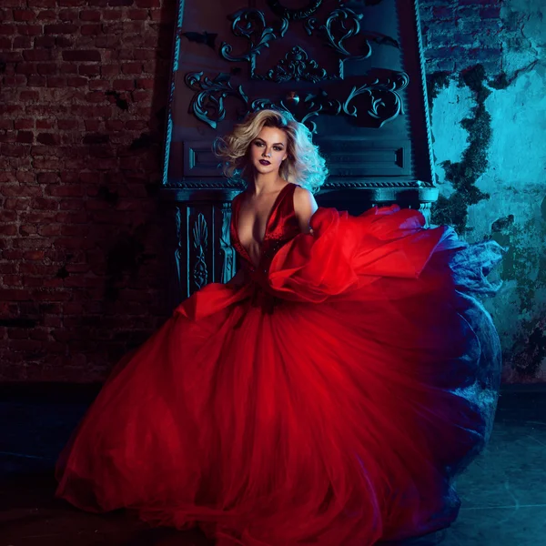 Modefoto der jungen großartigen Frau. läuft auf die Kamera zu. verführerische Blondine im roten Kleid mit flauschigem Rock — Stockfoto