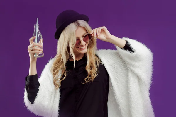 Jeune belle femme blonde au chapeau à la mode. Boire du soda à partir de bouteilles en verre. Joyeux et heureux — Photo