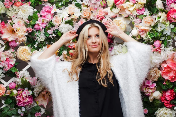 Junge schöne blonde Frau in modischen Hut auf floralem Hintergrund — Stockfoto